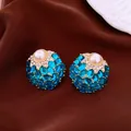 Close-up of vintage palace style blue crystal and pearl stud earrings on brown fabric - Gold Base / Light Blue