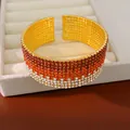 Primo piano di un bracciale rigido con sfumatura di strass rossi e bianchi di lusso. - Sfumatura Rosso Vino Oro
