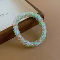 Detailed view of woven crystal beaded bracelet featuring green and amber faceted beads - Bracelet / Green-Coffee