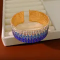 Primo piano di un elegante bracciale rigido elastico a più strati con strass blu sfumati - Sfumatura Blu Scuro Oro