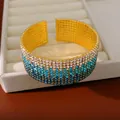 Primo piano di un bracciale a fascia dorato a più file con strass sfumati blu e bianchi. - Sfumatura Blu Cielo Oro