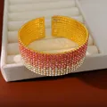 Primo piano di bracciale rigido aperto con strass sfumati rosa su vassoio gioielli - Sfumatura Rosa Oro