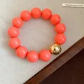 Bold orange chunky bead bracelet featuring a statement metallic gold bead for women - Bracelet / Pink