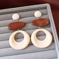 Dettaglio di orecchini geometrici in legno e resina su un vassoio per gioielli in velluto grigio - Stile Pendente Tondo Geometrico (HE34064) / Bianco-Caffè