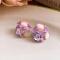 Close-up of purple butterfly stud earrings with crystal and pink cat-eye stones. - Purple