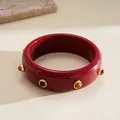 Detail of a retro burgundy resin bangle decorated with golden studs and tiger eye stones - Red Vintage Rivet Style