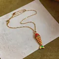 Dettaglio ravvicinato di un ciondolo a forma di pesce smaltato su catena dorata. - Collana-Oro-Rosso