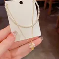 Elegante collana a due strati con girocollo di perle e raffinato ciondolo a cestino. - Collana Oro Con Perla Bianca