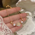 Dettaglio di bracciale a stella placcato oro con perle bianche e disco di zirconi - Oro