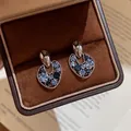 Close-up of vintage hollow earrings with blue rhinestones in a luxury jewelry box - Irregular Hollow Style (HE34319-1-) / One Pair / Silver Base Blue Stone