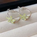 Detailed shot of silver hoop earrings with yellow-green resin flowers on a display tray. - Silver Needle / Silver-Yellow