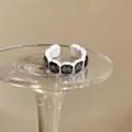 Dettaglio ravvicinato di un anello vintage esagonale con gemme scure e montatura bianca. - Esagonale Intarsiato (HR3368) / Bianco-Grigio