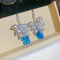 Dettaglio di orecchini a perla a forma di uva con zirconi e perline blu traslucide. - Blu
