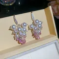 Dettaglio macro degli orecchini pendenti a uva con perle e zirconi stile francese - Rosa