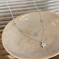 Detailed macro shot of a double-layer silver star necklace featuring a blue zircon pendant - Star Pendant Double Layer Necklace / Silver