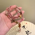 Macro detail of multilayered beaded bracelet with pink rhodonite and tiger eye stones. - Pink