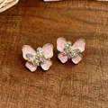 Close-up detail of pink enamel butterfly earrings with sparkling rhinestone accents. - Gold-Pink