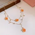 Close-up detail of Y-shaped double layer gold necklace with orange enamel flowers and pearls. - Necklace (HN12502) / Gold-Orange