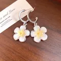 Dettaglio macro di orecchini a cerchio a C in argento con pendenti a fiore in smalto bianco - Giallo
