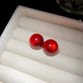 Close-up detail of vibrant red round resin stud earrings in a white velvet jewelry box - Silver Earring Post Style / Red