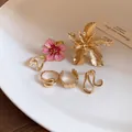 Dettaglio del set di anelli a fiore dorati con fiore in smalto rosa e fedine minimali - Fiore 3D / Oro-Rosa