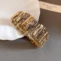 Close-up detail view of a vintage gold-tone irregular segmented metal cuff bracelet - Gold
