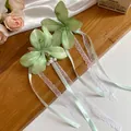 Détail des pinces à cheveux en fleurs de tissu vert clair avec rubans de dentelle élégants. - Pinces à cheveux bec de canard / Vert