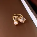 Detailed macro view of a golden open ring with elegant oval champagne crystal and pearl - Open Ring / Gold Brown