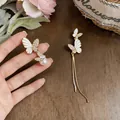 Detailed close-up of asymmetrical white enamel butterfly earrings with rhinestones - Gold White