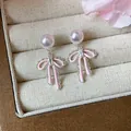Close-up of pink enamel bow pearl stud earrings with zircon inside a jewelry box - Bowknot Pearl Earrings / Pink