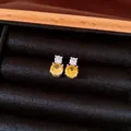 Close-up of elegant silver stud earrings with yellow and clear cubic zirconia stones - Yellow