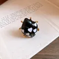 Macro view of black enamel ladybug ring with white heart dots and gold plating finish - Ladybug Style / Black