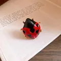 Detail shot of an enamel ladybug ring with red finish and black heart-shaped spots. - Ladybug Style / Red