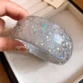 Detailed macro view of a resin bangle bracelet with holographic stars and glitter - Gray