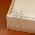 Close-up of silver needle four-leaf clover flower stud earrings with sparkly cubic zirconia. - White