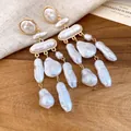 Detailed macro shot of vintage baroque pearl drop earrings on a warm wooden background - Gold-White (HE33540)