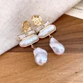 Macro view of vintage Baroque pearl earrings featuring hammered gold and crystal accents - Gold-White (HE33541)