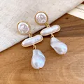 Detailed macro view of vintage gold baroque pearl drop earrings on a textured wooden surface. - Gold-White (HE33544)