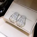 Detaillierte Nahaufnahme von eleganten Zirkon- und Perlenohrsteckern in einer Luxus-Geschenkbox - Silber