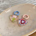 Detailed view of colorful heart-shaped drip oil glass earrings on a ceramic plate - Multicolor Asymmetric Heart Flower Style (HE32451)