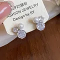 Detailed macro view of elegant flower shaped zircon and pearl stud earrings on card - White