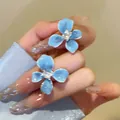 Macro detail shot of elegant sea salt blue flower stud earrings with a central sparkling crystal - Silver Earring Post Style / Sea Salt Blue