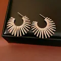 Detailed macro view of gold C-shaped sunburst earrings with radiant metallic bar texture - Light Coffee Gold