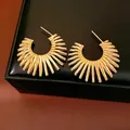 Detailed view of gold-colored sunburst C-shaped earrings with textured finish - Gold