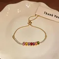 Detailed close-up of a gold-plated adjustable slider bracelet with vibrant multicolor zircon stones - Colorful Zirconia Bracelet - Vertical / Gold