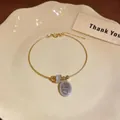 Detail of gold-colored bracelet featuring a cat's eye stone and shimmering oval charm - Two-tone Gold Silver