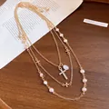 Detailed view of layered gold necklace featuring pearl beads and a crystal cross pendant - Gold