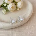 Dettaglio ravvicinato di eleganti orecchini a fiocco d'argento con perla bianca - Stile Pendente di Perla con Fiocco / Argento