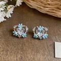 Macro view of heart-shaped earrings with blue enamel flowers and clear stones - Enamel Flower Heart Style / One Size / Silver Earring Post - Silver - Blue
