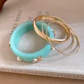 Detailed view of mint green resin bangle with starfish charms and gold metal bracelets - Gold-Blue
